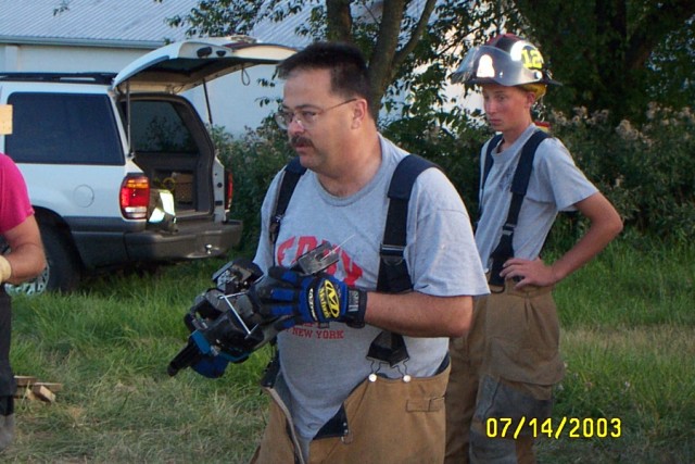 Firefighter Mike Predmore explains power tool operation, while Firefighter Danny O'Connell listens intently