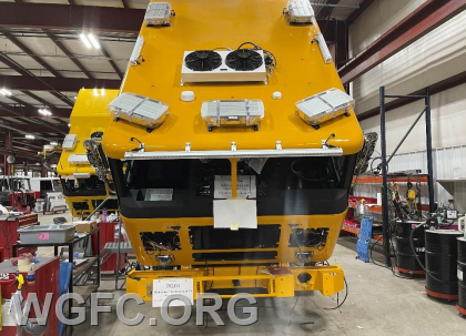 With the cab mounted to the frame, work on the roof emergency lighting and HVAC equipment is visible.