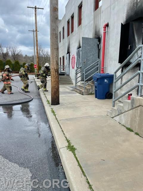 Training crews advance a charged hose line into the building.