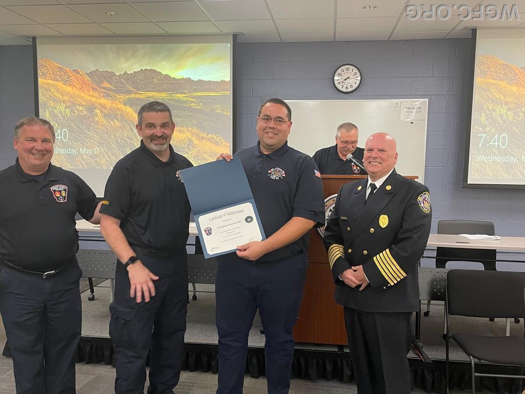 Lieutenant Kloss presents Firefighter Hill his certificate.