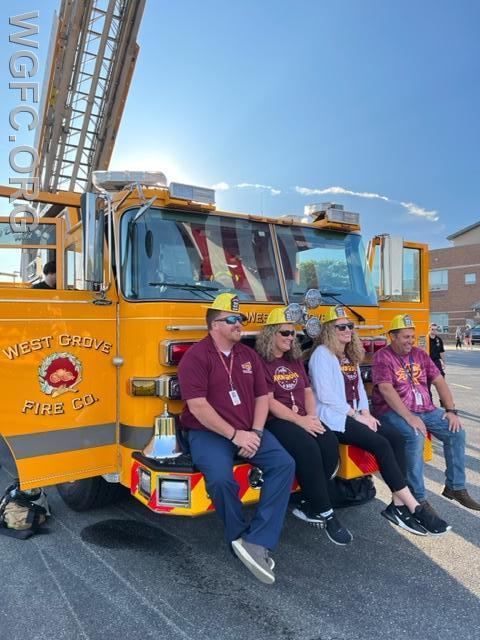 Principal Kimberly Hall (in white) and some of her team pose on Ladder 22 with their WGFC fire hats.